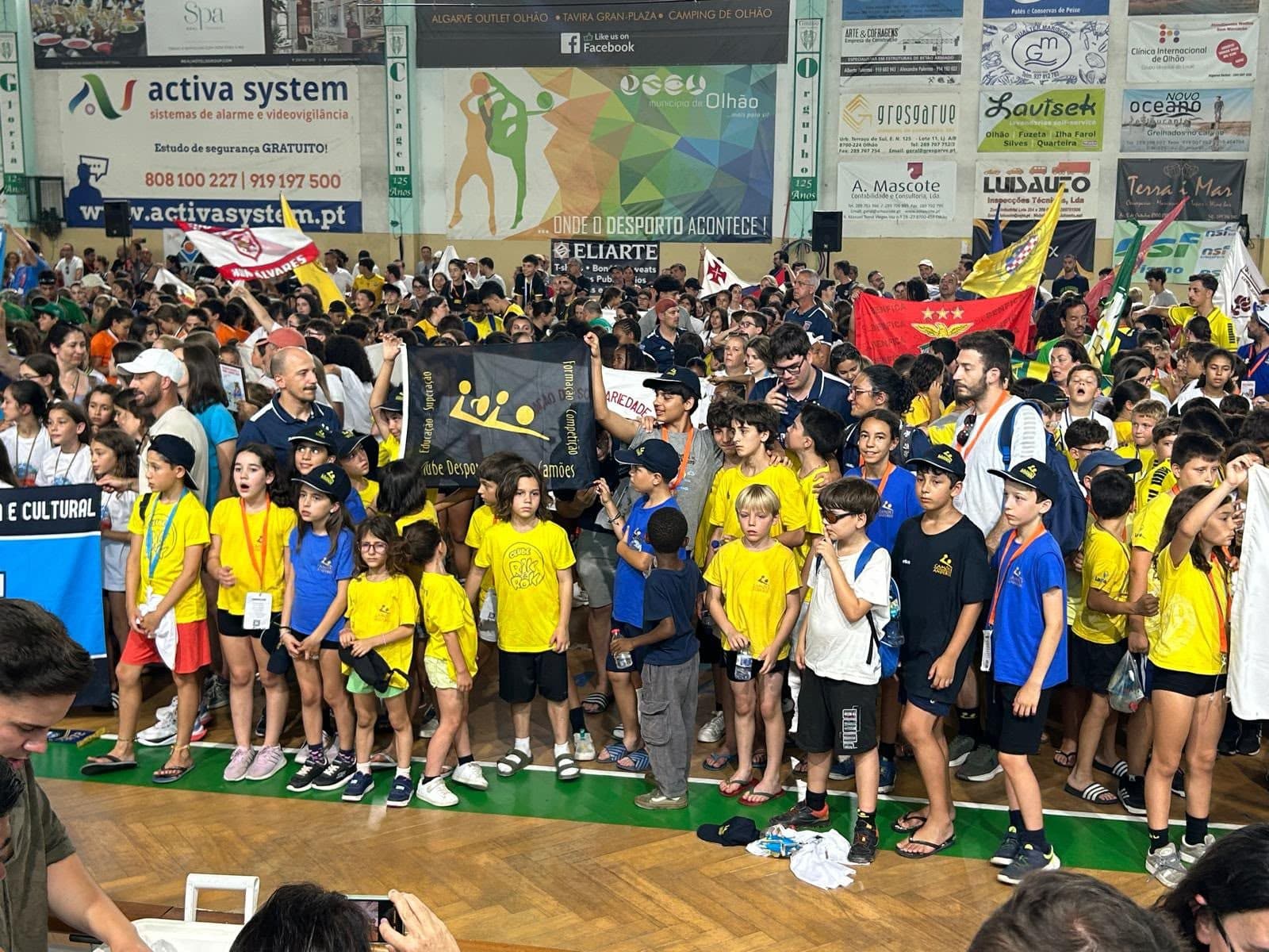 Jovens atletas do Camões Andebol com a bandeira do clube num torneio